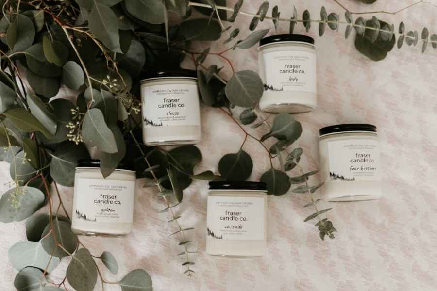 soy wax candles made from soy wax flakes lying on a blanket surrounded by dried eucalyptus